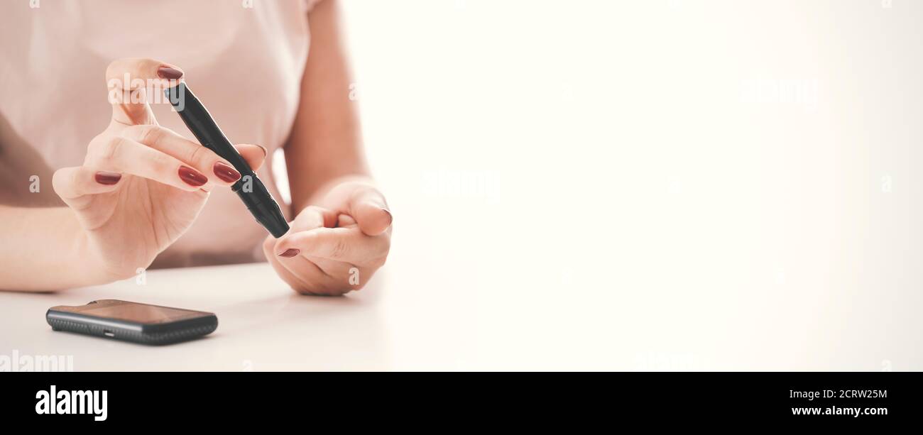 Donna che preleva il campione di sangue con penna a lancetta. Diabete, concetto di assistenza sanitaria. Sfondo dell'immagine con spazio di copia Foto Stock