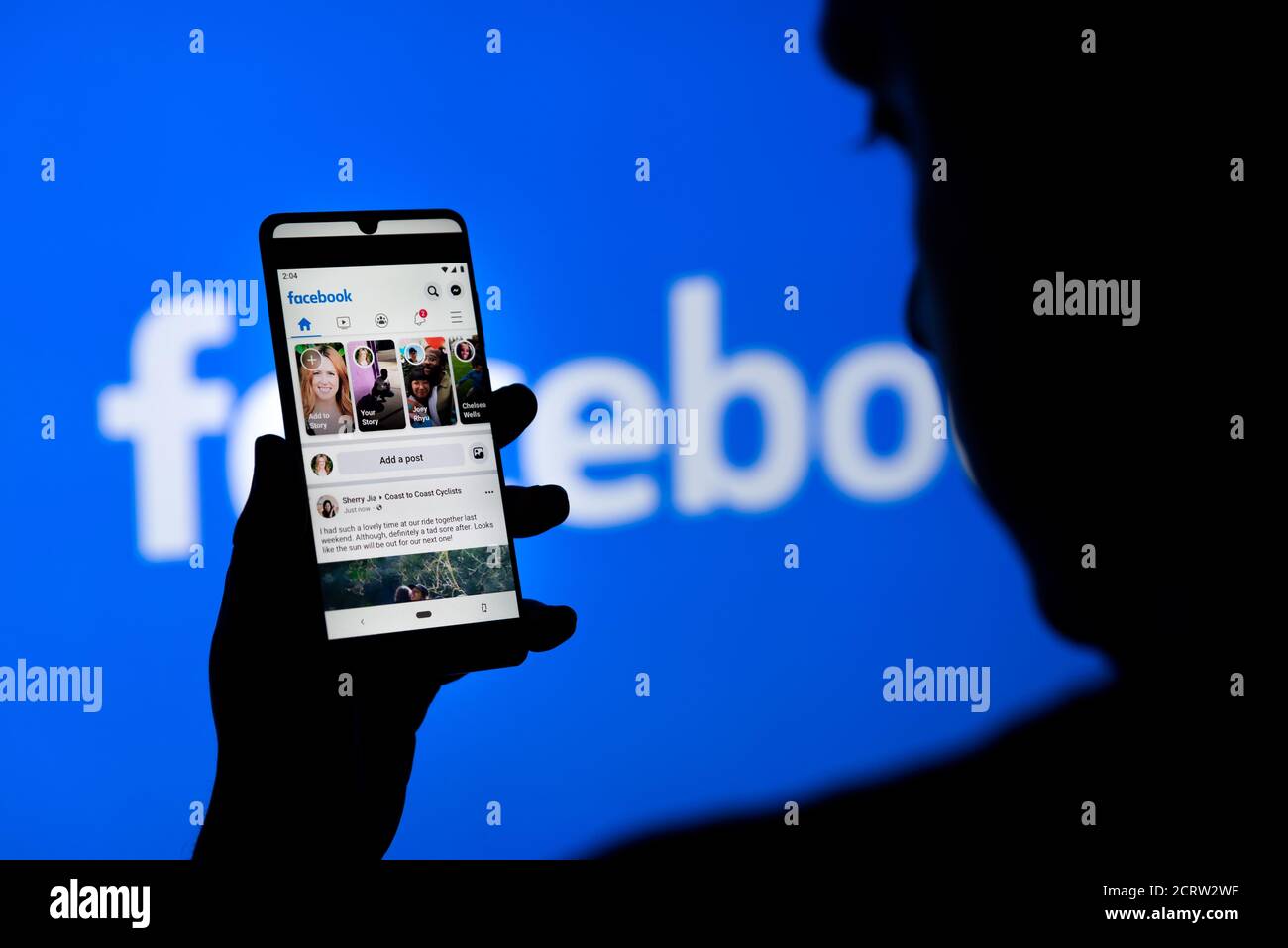 Wroclaw, Polonia - 16 SETTEMBRE 2020: Uomo che tiene smartphone con l'app mobile Facebook sullo schermo, logo Facebook sullo sfondo. Facebook è la calza più popolare Foto Stock