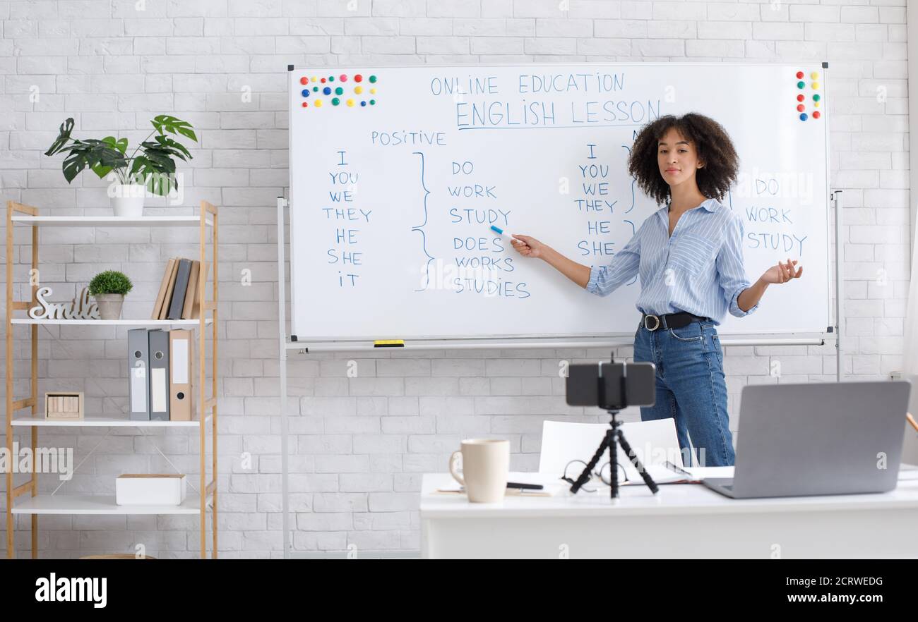 Insegnante di inglese online a casa. Ritratto di donna afroamericana, scrivendo a bordo in classe Foto Stock