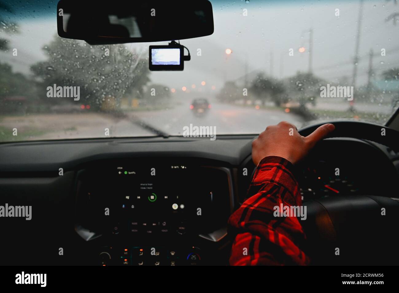 Uomo che guida un'auto sotto la pioggia durante la guida notturna condizioni meteorologiche avverse sulla strada Foto Stock
