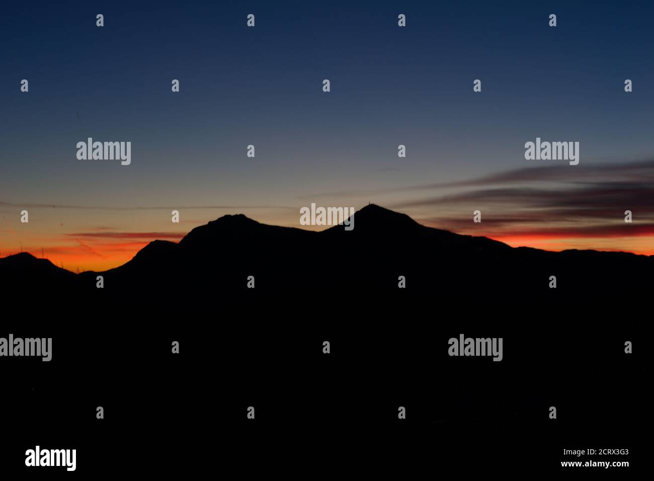 scenico tramonto arancione in trentino con silhuette di montagna a blu ora Foto Stock