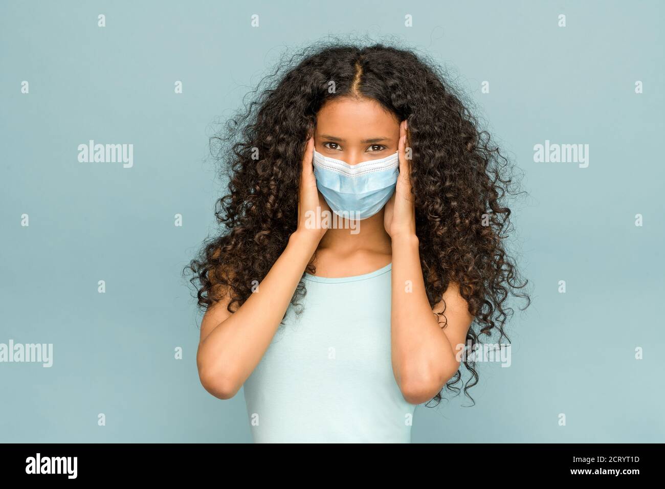 Attraente giovane donna dominicana con lunghi capelli ricci che indossa un Maschera facciale durante il coronavirus o Covid-19 pandemia in A. Concetto del nuovo normale l Foto Stock