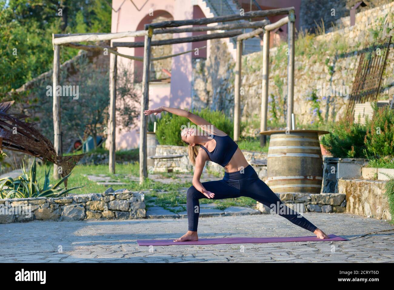 Donna che fa un lungo angolo di yoga posa stretching e. tonificare i muscoli del nucleo all'aperto nel giardino in un concetto di salute e fitness Foto Stock