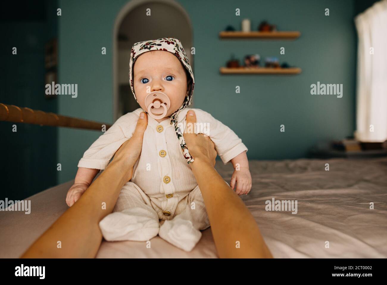 Bambino in un cofano seduto a letto con l'aiuto di un bambino dalle mani di una madre Foto Stock