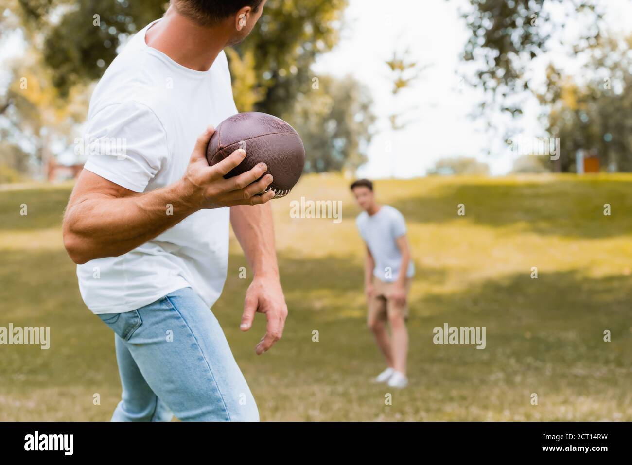 fuoco selettivo dell'uomo che lancia la sfera di rugby al figlio dentro parcheggio Foto Stock