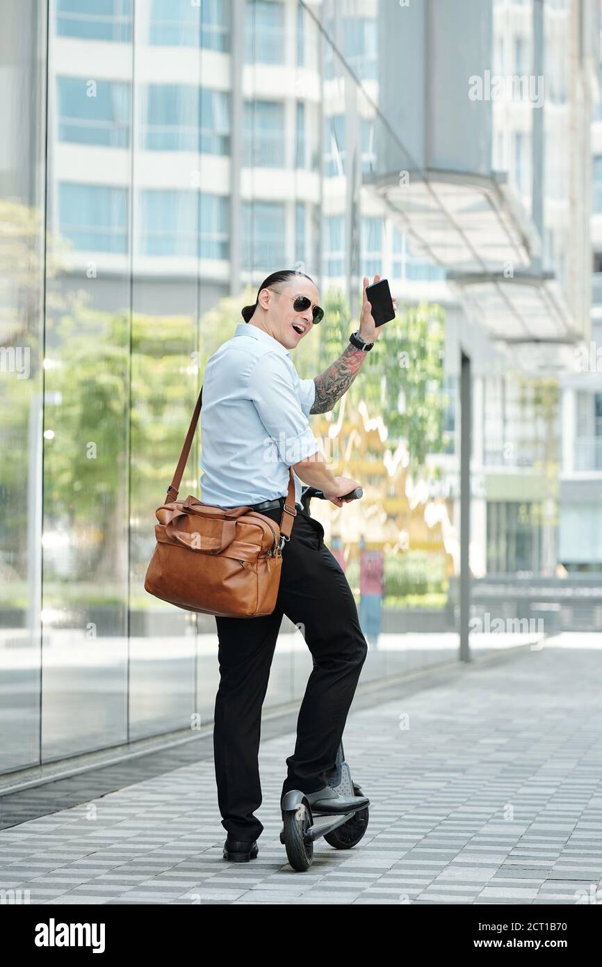 Uomo d'affari elegante in piedi su scooter Foto Stock