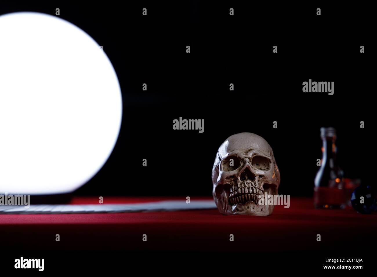 Cranio sul tavolo del cassiere di fortuna con palla di cristallo brillante sul lato sinistro. Foto Stock