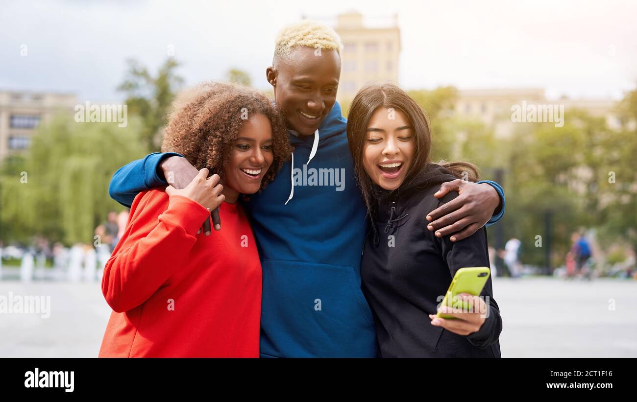Multi etnia amici esterni guardare lo schermo dello smartphone. Diverse persone di gruppo Afro american asian trascorrere il tempo insieme multirazziale maschio studien femmina Foto Stock
