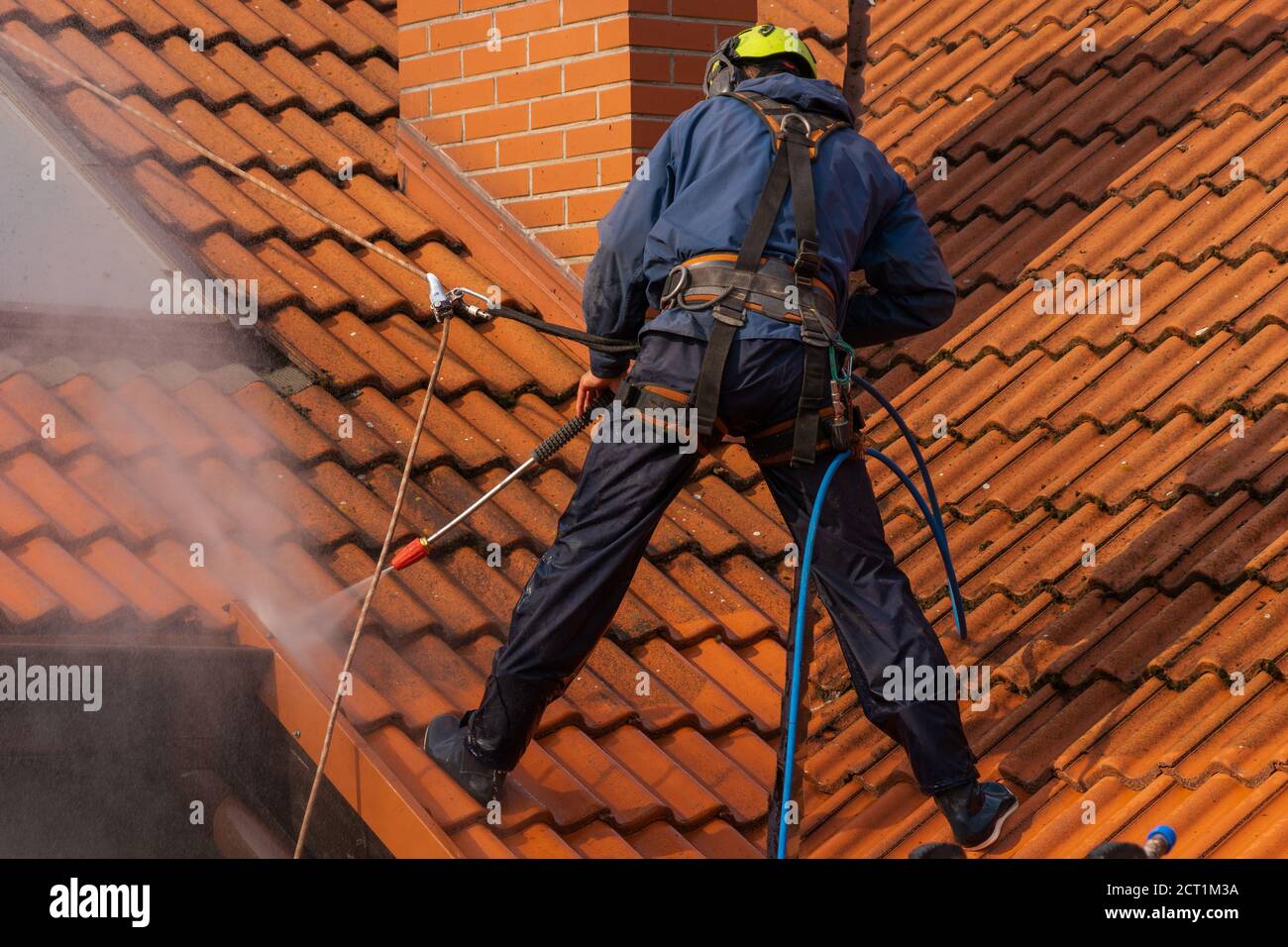 operatore che lava il tetto con acqua pressurizzata Foto Stock