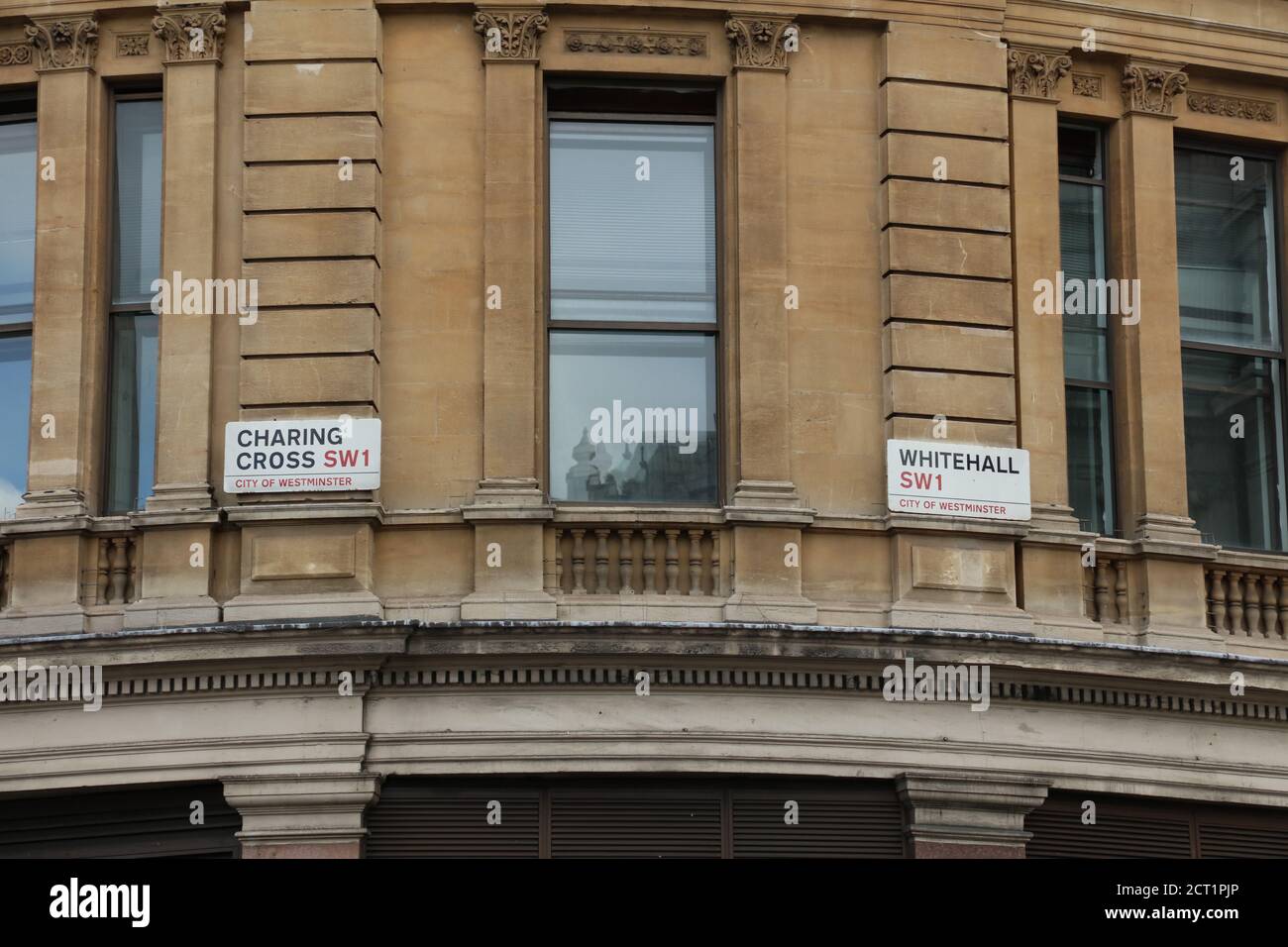 Due cartelli stradali visti insieme sono fissati in alto contro un muro all'aperto all'intersezione di Charing Cross e Whitehall, Londra, Regno Unito. Foto Stock