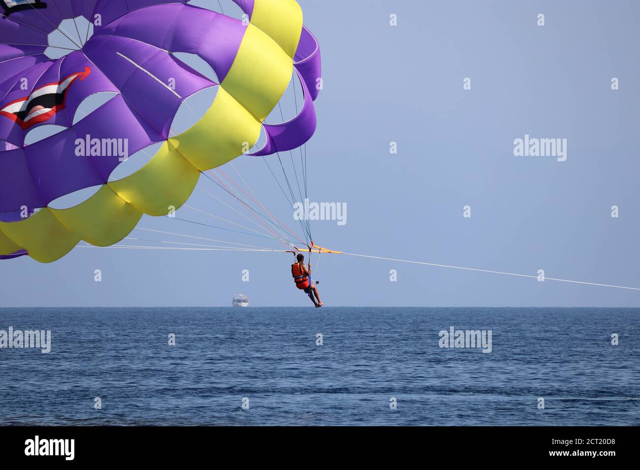 Parasailing sul mare, uomo con action camera che vola nel cielo blu, fuoco selettivo sul paracadute. Concetto di vacanza, sport estremi su una spiaggia Foto Stock