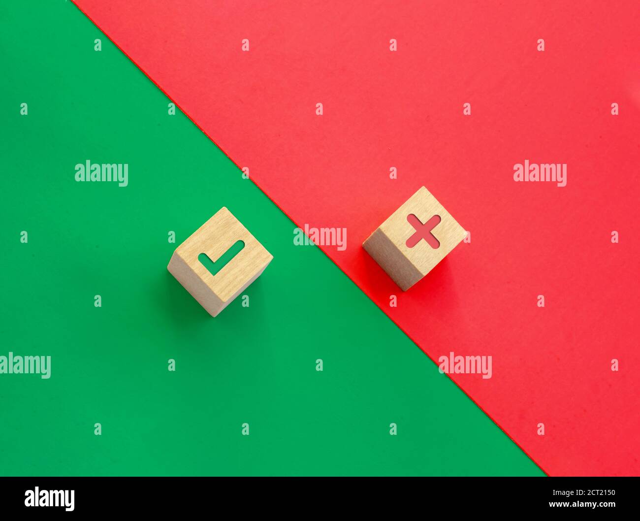 Un paio di cubi di legno con icone di controllo e di canti errati su sfondo verde e rosso. Concetto giusto e sbagliato. Foto Stock