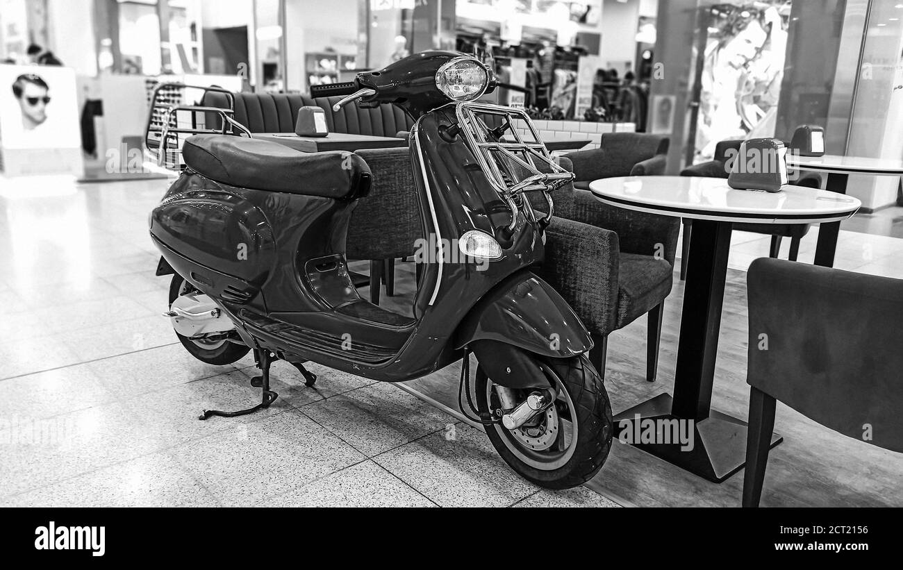 Foto in bianco e nero sullo sfondo di un centro commerciale. Scooter classico sullo sfondo di un caffè vuoto. Sfondo vintage. Stile vintage Foto Stock