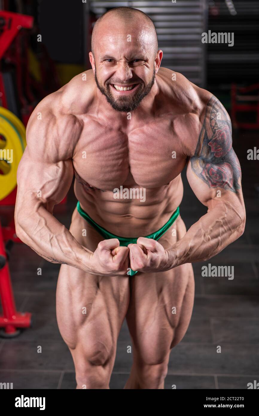 Primo piano di potente uomo muscolare in posa con contrazione muscolare in palestra Foto Stock