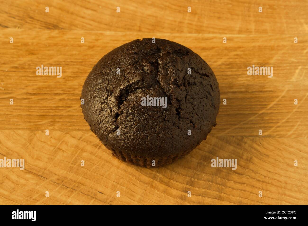 Un cupcake color caffè si trova su un asse di legno Foto Stock