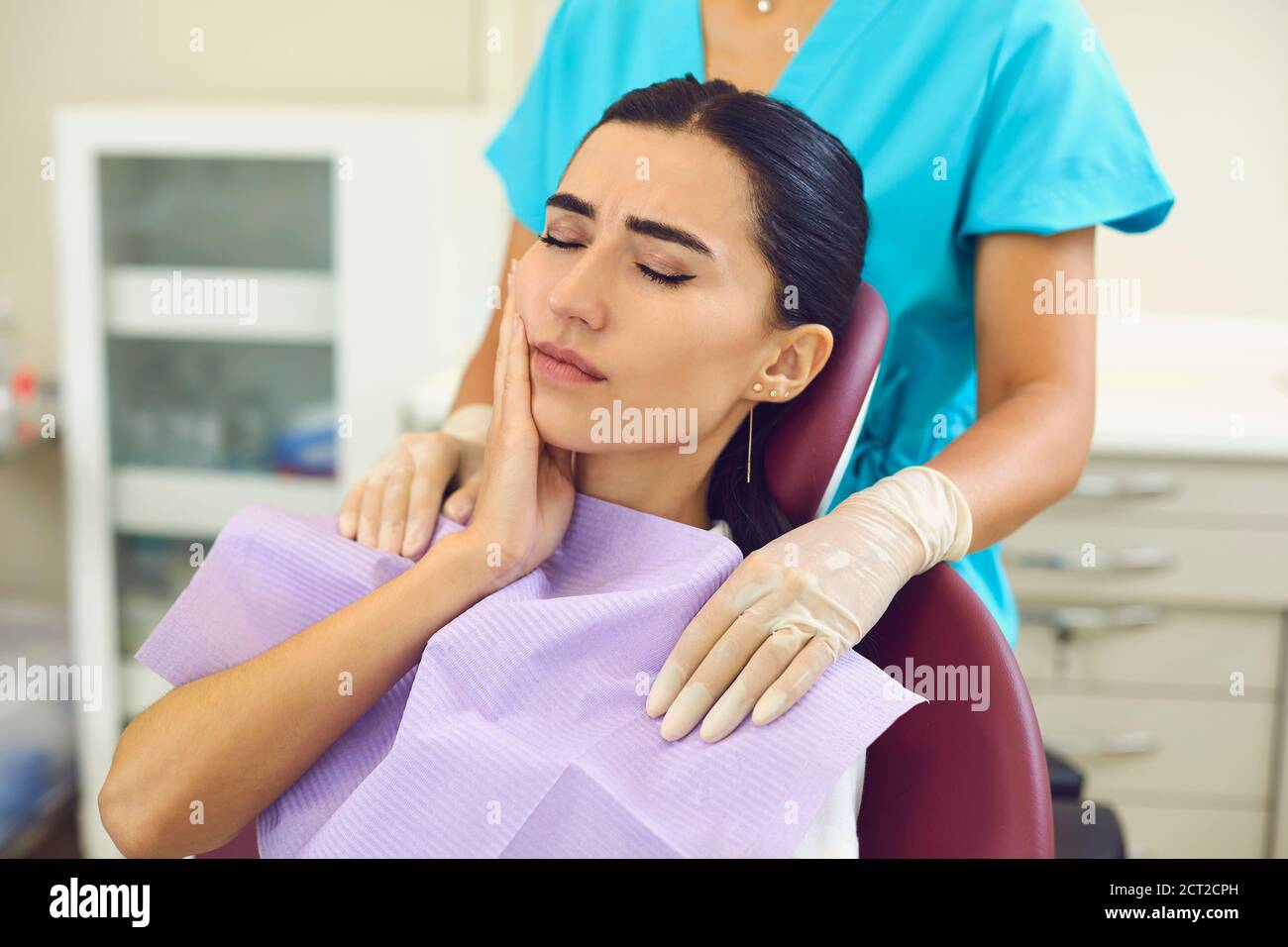 La giovane donna è seduta su una sedia dentista e soffre di gravi mal di denti. Foto Stock