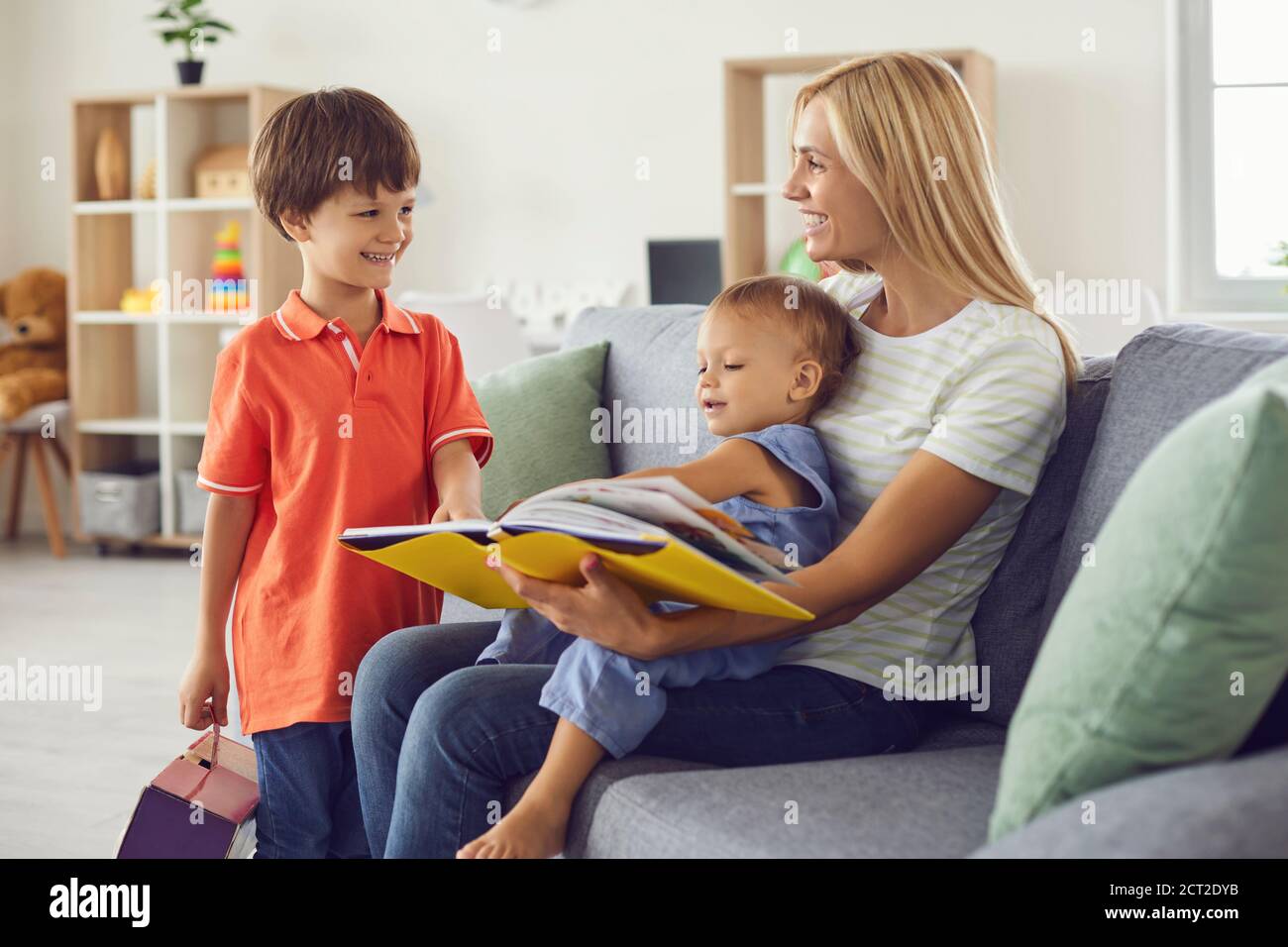 Buon libro di lettura della mamma delle fiabe al suo piccolo i bambini si siedono su un comodo divano a casa Foto Stock