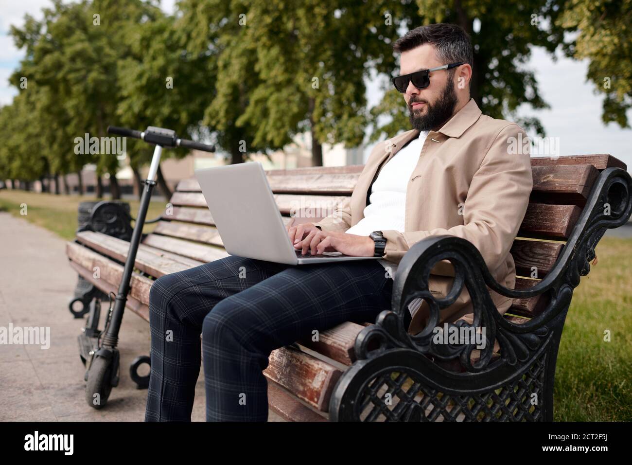 Giovane uomo d'affari bearded in casualwear astuto e gli occhiali da sole che navigano dentro la rete Foto Stock