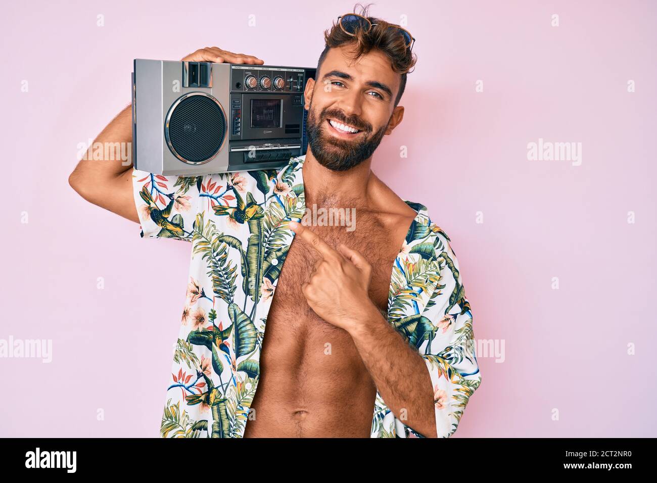 Giovane uomo ispanico che indossa abiti estivi reggendo il boombox, ascoltando musica sorpreso con la mano sulla testa per errore, ricordare errore. dimenticato, cattivo mem Foto Stock