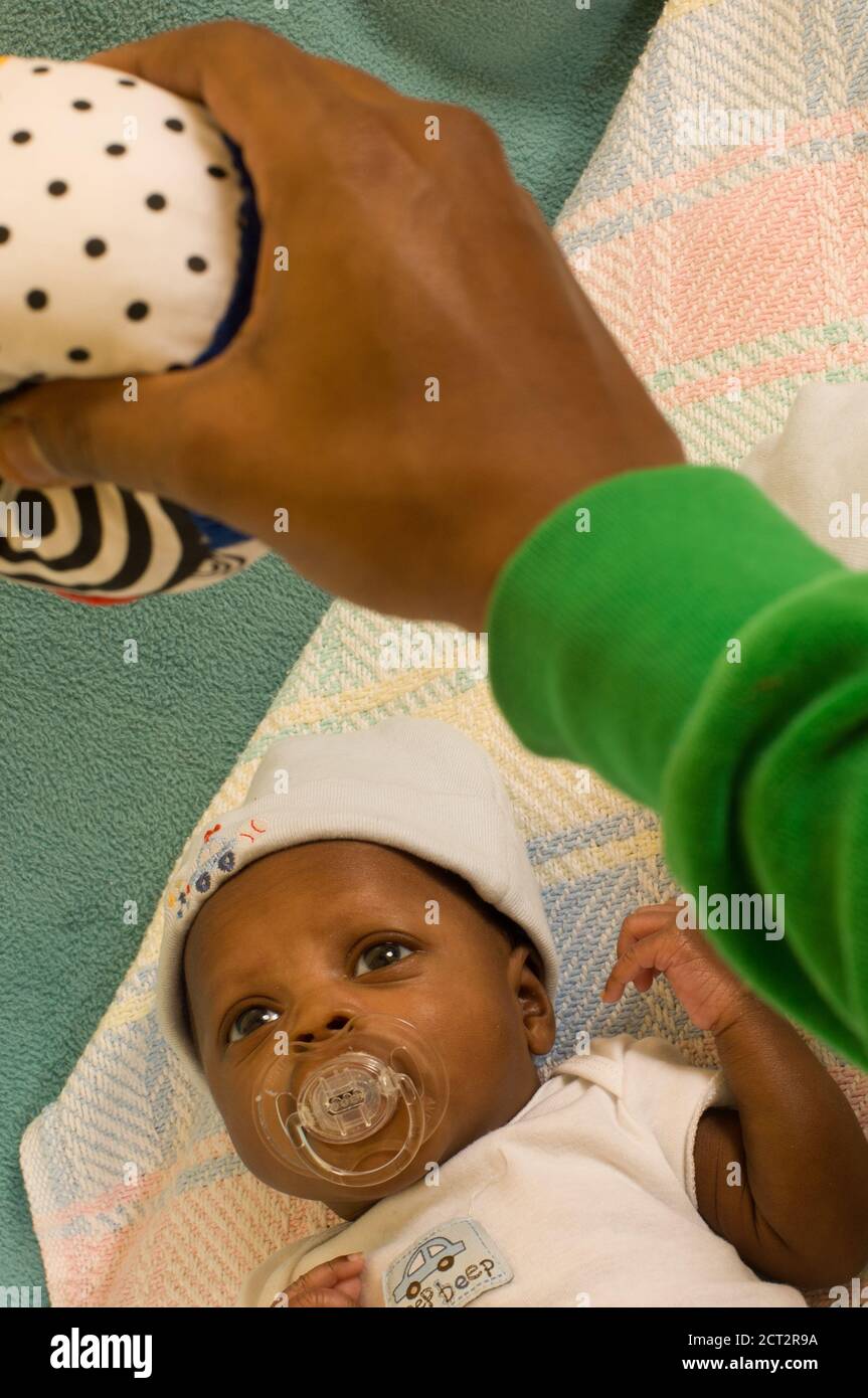 bambino neonato di 6 settimane un mese di allarme prematuro guardando il giocattolo penzolante Foto Stock
