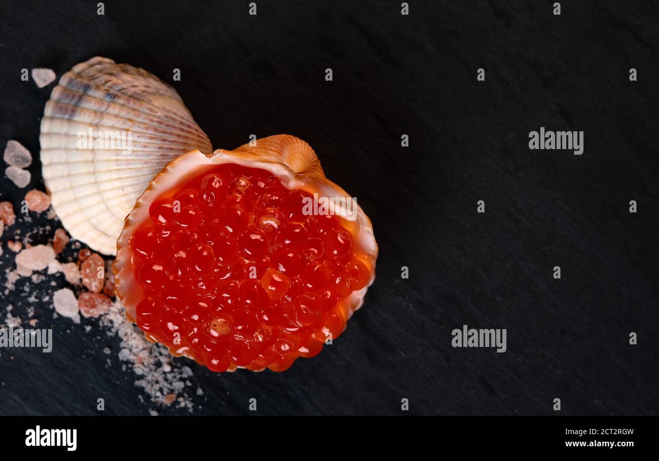 Caviale rosso in conchiglia su superficie di granito. Vista dall'alto. Foto Stock