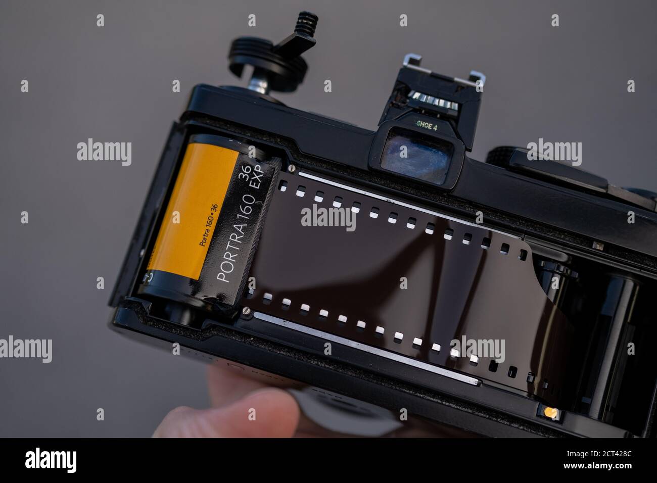 Una mano tiene una fotocamera reflex analogica con il retro aperto, mostrando la pellicola a colori Kodak Portra 160 caricata sul retro. Foto Stock