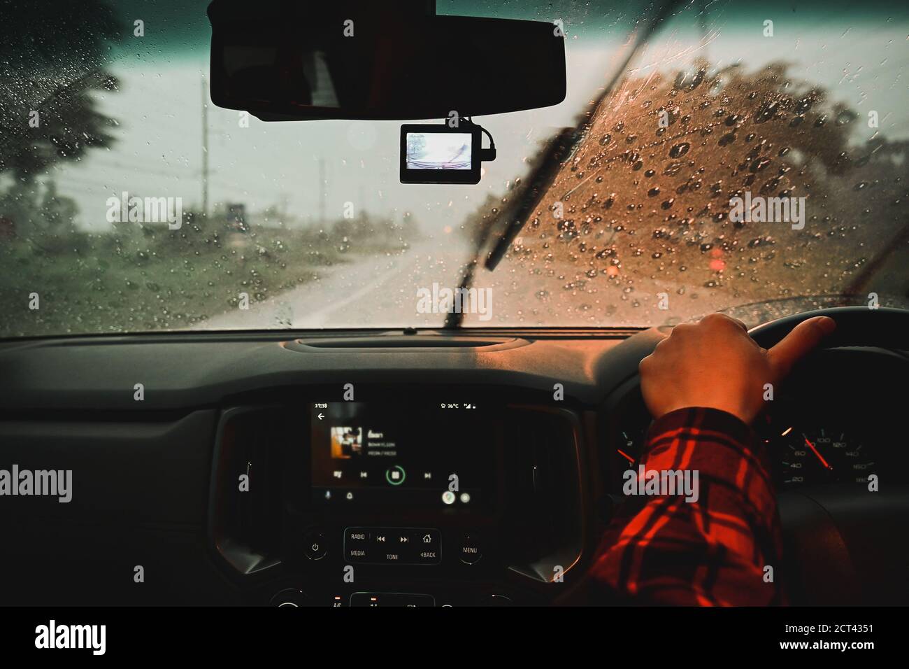 Uomo che guida un'auto sotto la pioggia durante la guida notturna condizioni meteorologiche avverse sulla strada Foto Stock