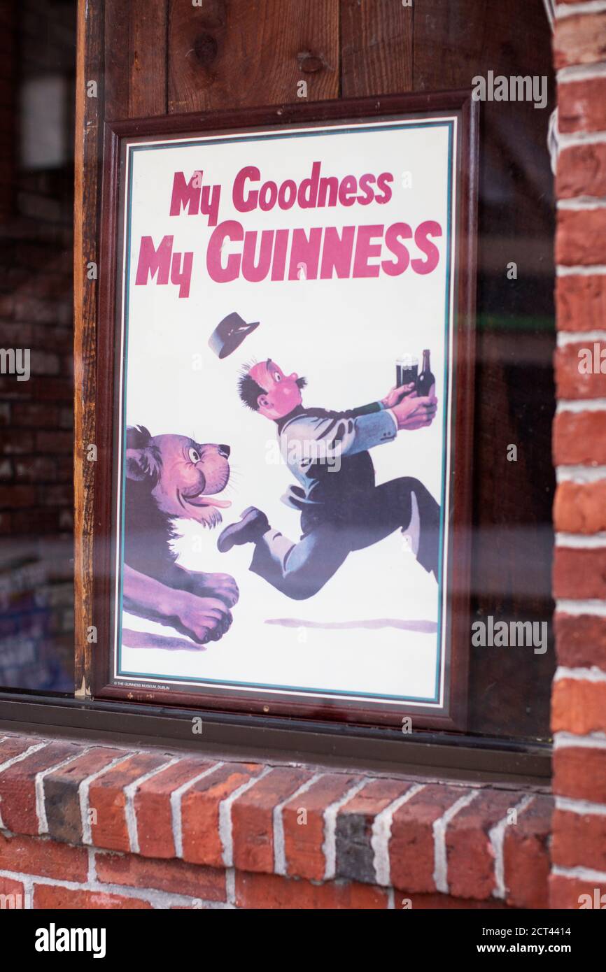 Un vecchio manifesto di pubblicità sbiadito Guinness incorniciato in una finestra a Lowell, Massachusetts, Stati Uniti. Foto Stock