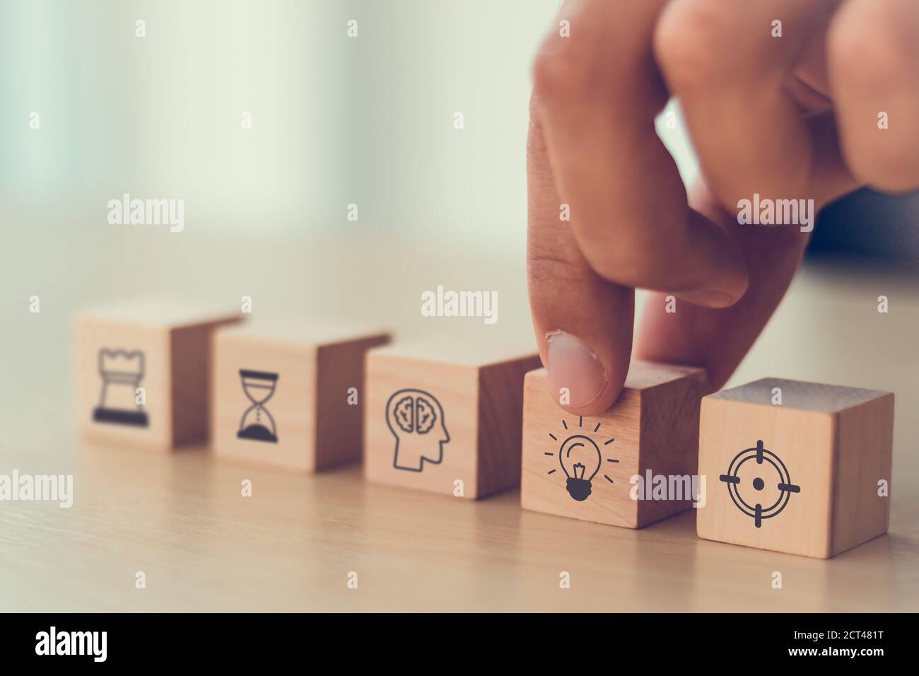 Uomo di affari mano che organizza legno blocco. Icona di strategia di affari compreso elemento con obiettivo, idea, leadership, gestione del tempo, conoscenza, Initi Foto Stock