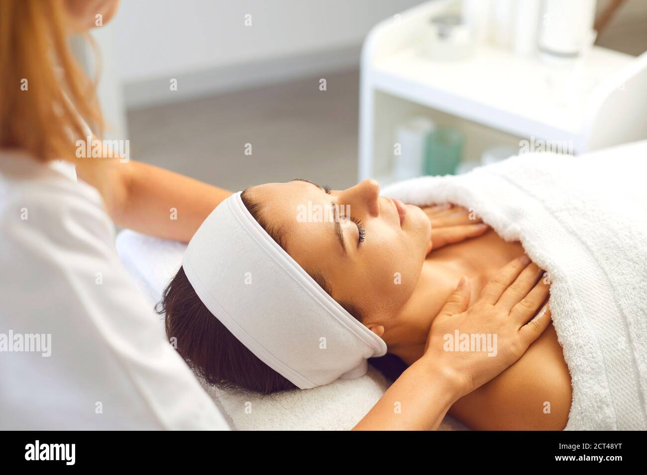 Paziente di donna che ottiene massaggio rilassante manuale ringiovanente per il viso e. spalle del terapeuta Foto Stock