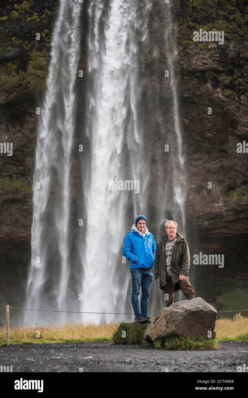 Padre e figlio a Seljalandsfoss, una famosa cascata appena fuori dalla Route 1 in Sud Islanda (Sudurland), Europa Foto Stock