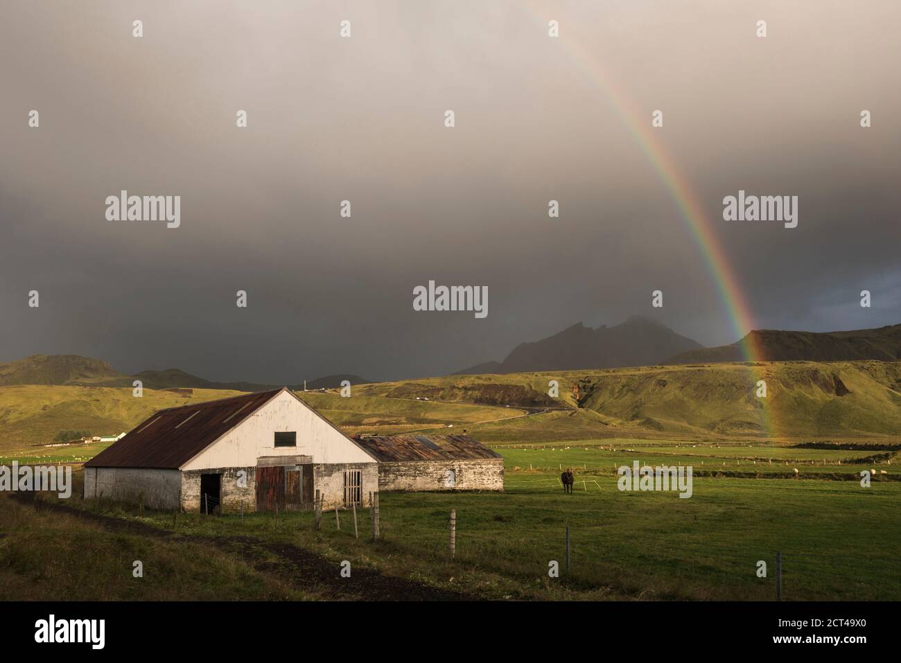 Tipici edifici rurali islandesi sotto un arcobaleno presso la penisola di Dyrholaey, vicino a Vik, Islanda del Sud (Sudurland), Europa Foto Stock