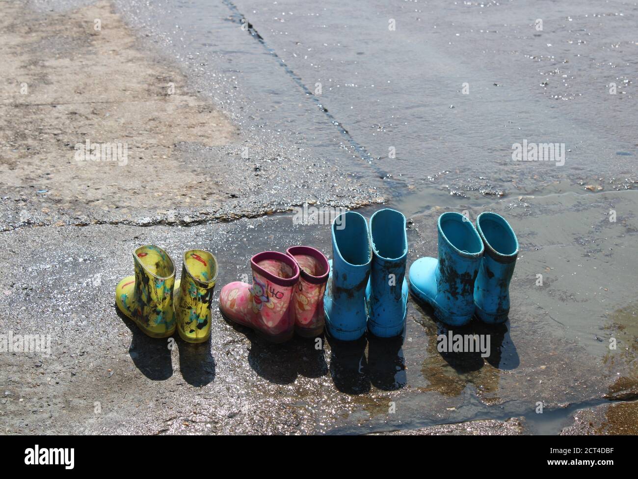 Quattro paia di stivali in gomma per bambini su una barca bagnata rampa Foto Stock
