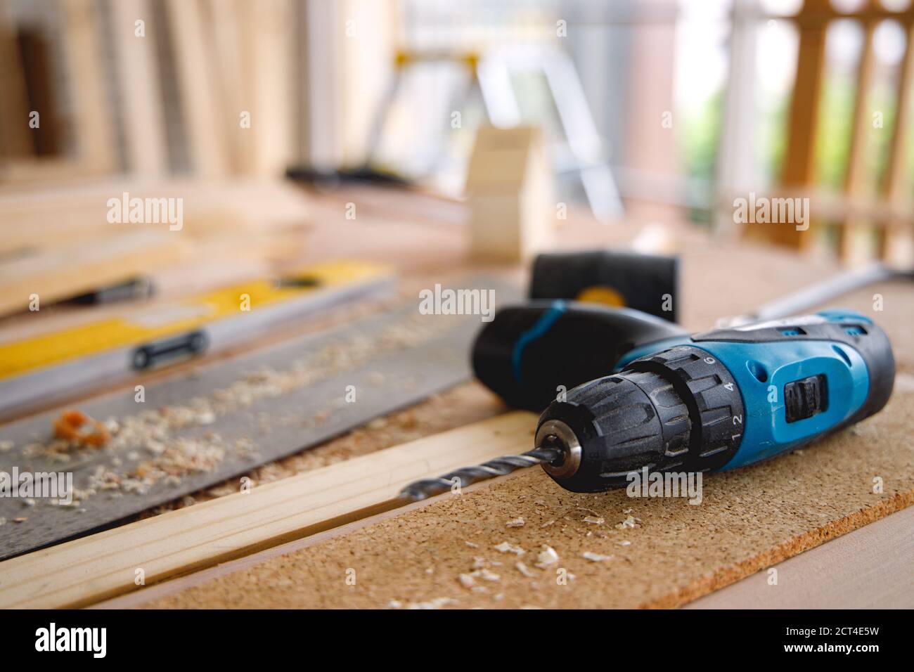 Trapano elettrico blu, sul tavolo di legno pieno di segatura, utilizzando per la lavorazione del legno o la riparazione di interni domestici. Foto Stock
