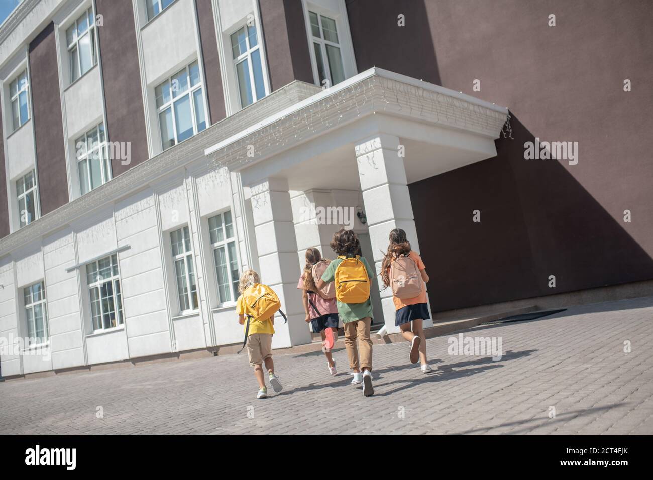 Bambini con zaini che giocano nel cortile dopo le lezioni Foto Stock