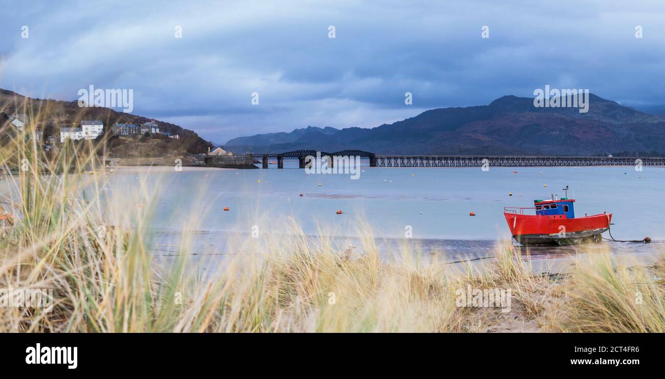 Vecchia barca da pesca e Barmouth Bridge nel porto di Barmouth con le montagne Cader (Cadair) dietro (parte del Parco Nazionale di Snowdonia), Gwynedd, Galles del Nord, Galles, Regno Unito, Europa Foto Stock