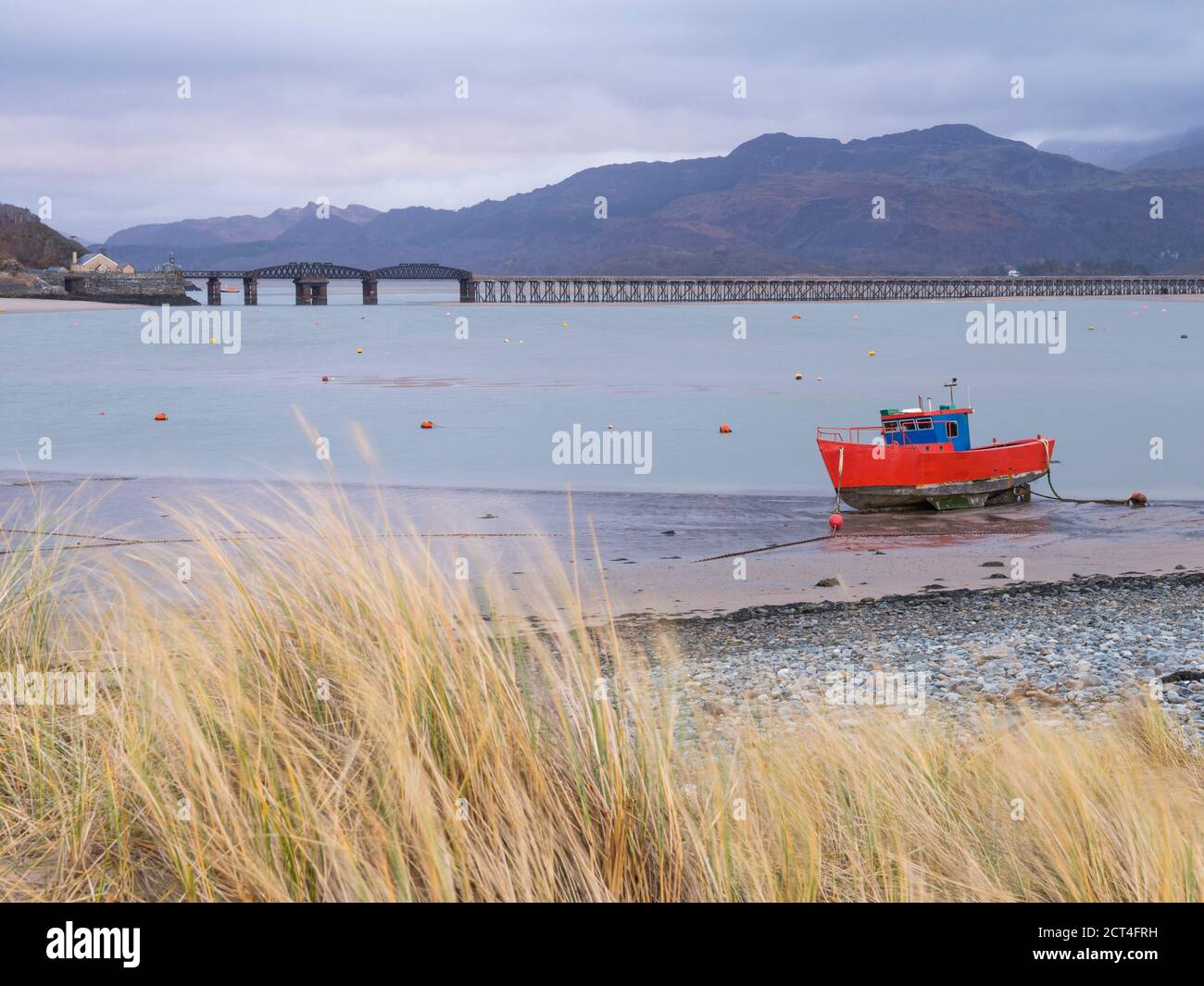 Vecchia barca da pesca e Barmouth Bridge nel porto di Barmouth con le montagne Cader (Cadair) dietro (parte del Parco Nazionale di Snowdonia), Gwynedd, Galles del Nord, Galles, Regno Unito, Europa Foto Stock