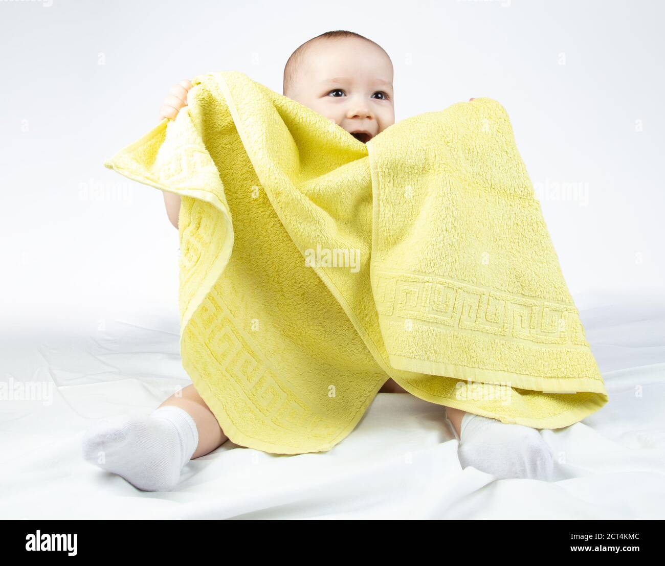 Foto di un bambino sorridente di undici mesi con asciugamano giallo Foto Stock