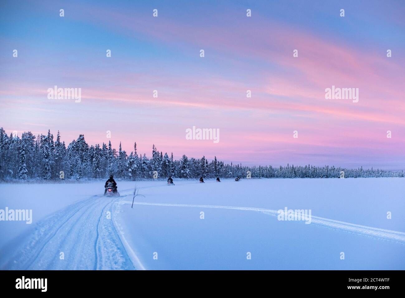 Escursioni in motoslitta sul lago ghiacciato al tramonto a Torassieppi, Lapponia, Finlandia Foto Stock