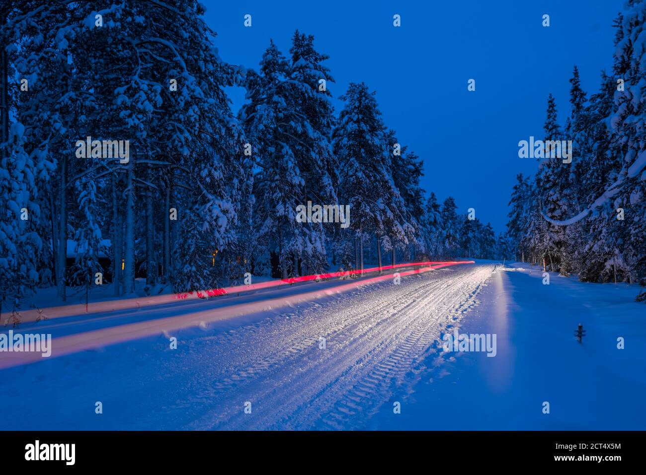 Condizioni stradali pericolose, guida un'auto di notte su una strada invernale ricoperta di neve ghiacciata nel Circolo polare Artico di Lapponia, Finlandia Foto Stock