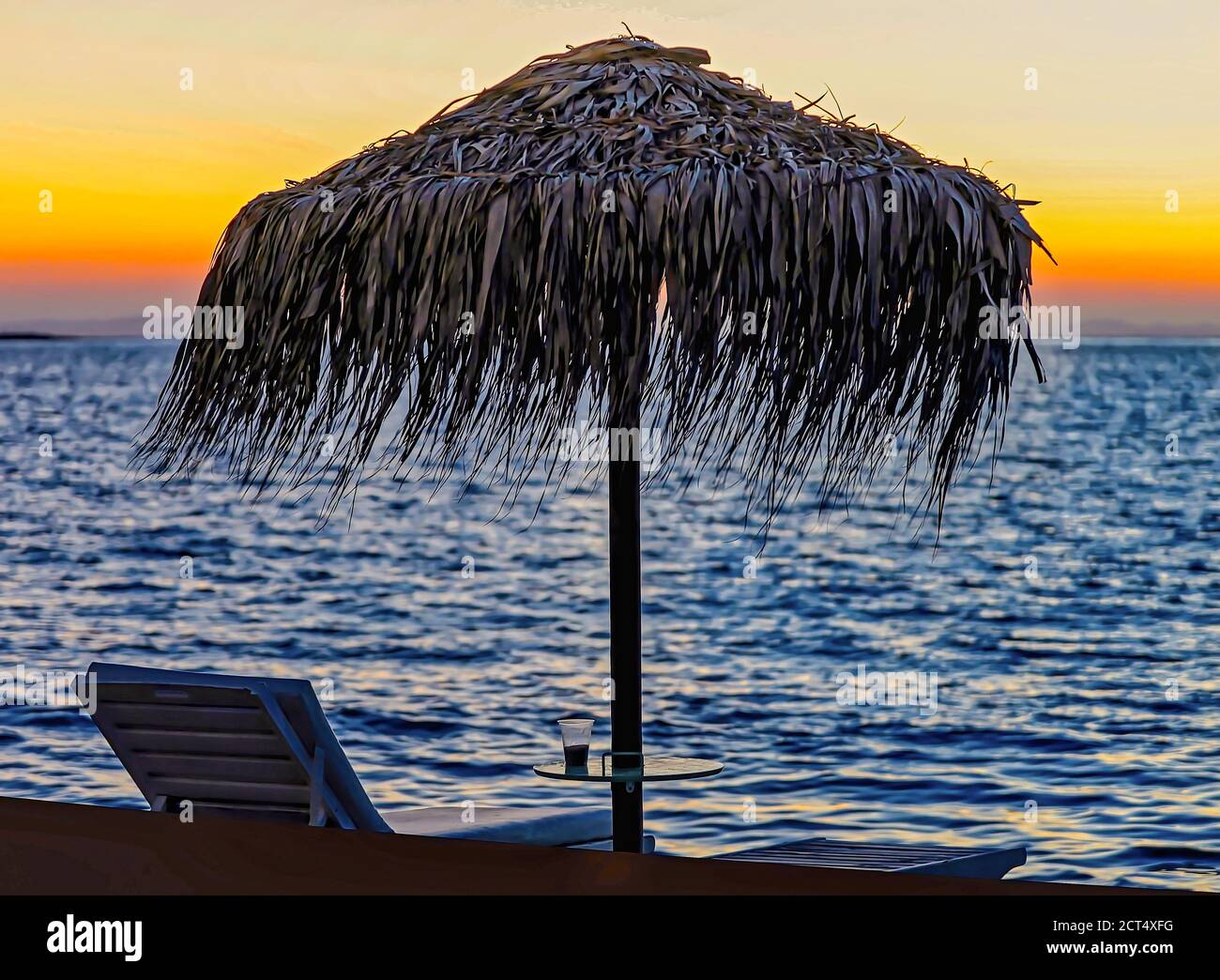 Seascape al Dawn. Isolato. Sagoma di ombrello di paglia e sdraio sulla spiaggia di un'isola greca al tramonto. Fotografia stagcape. Immagine stock. Foto Stock