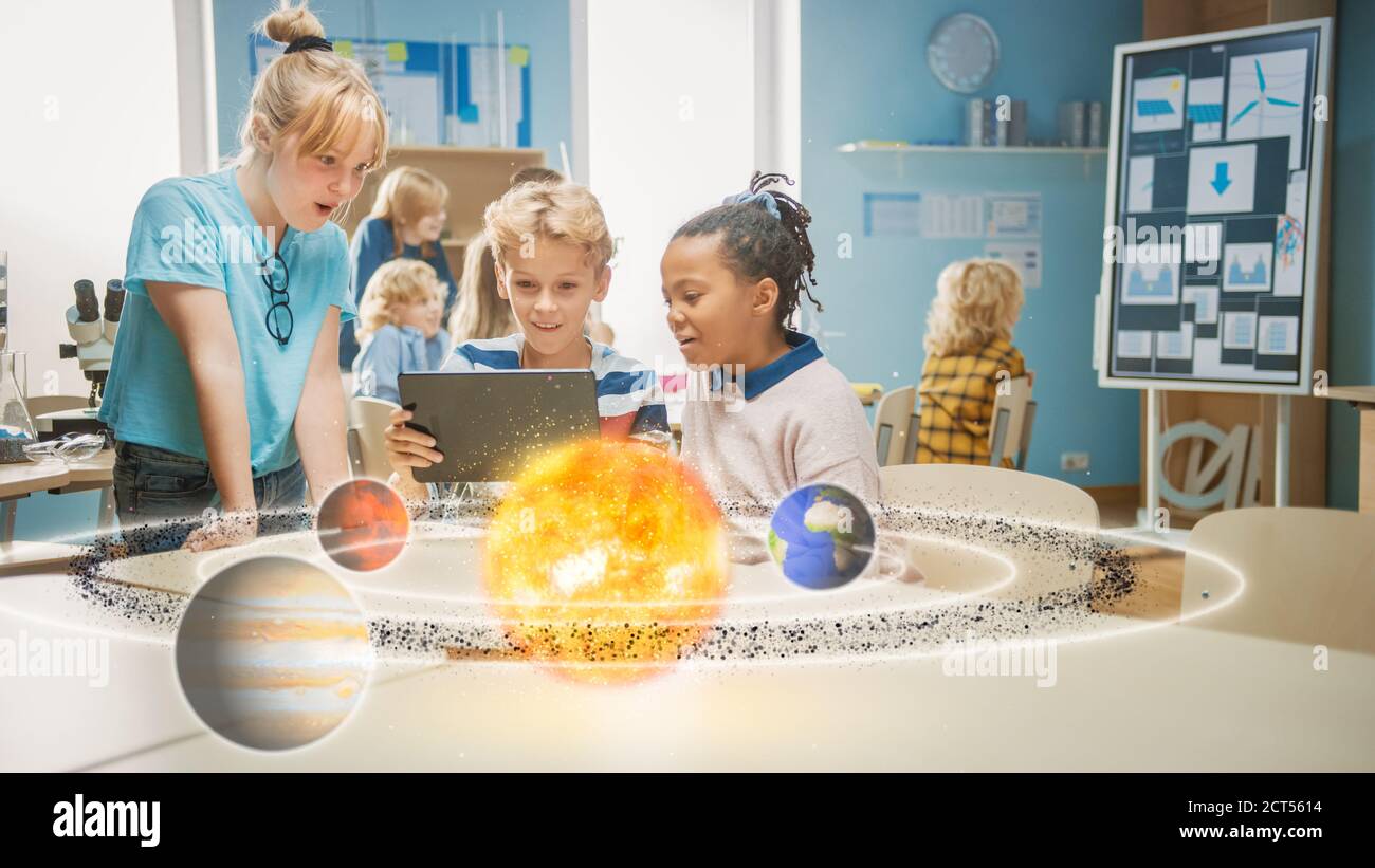 Tre diversi ragazzi della scuola in Science Class utilizzano il computer tablet digitale con il software di realtà aumentata, guardando l'animazione 3D didattica di Foto Stock