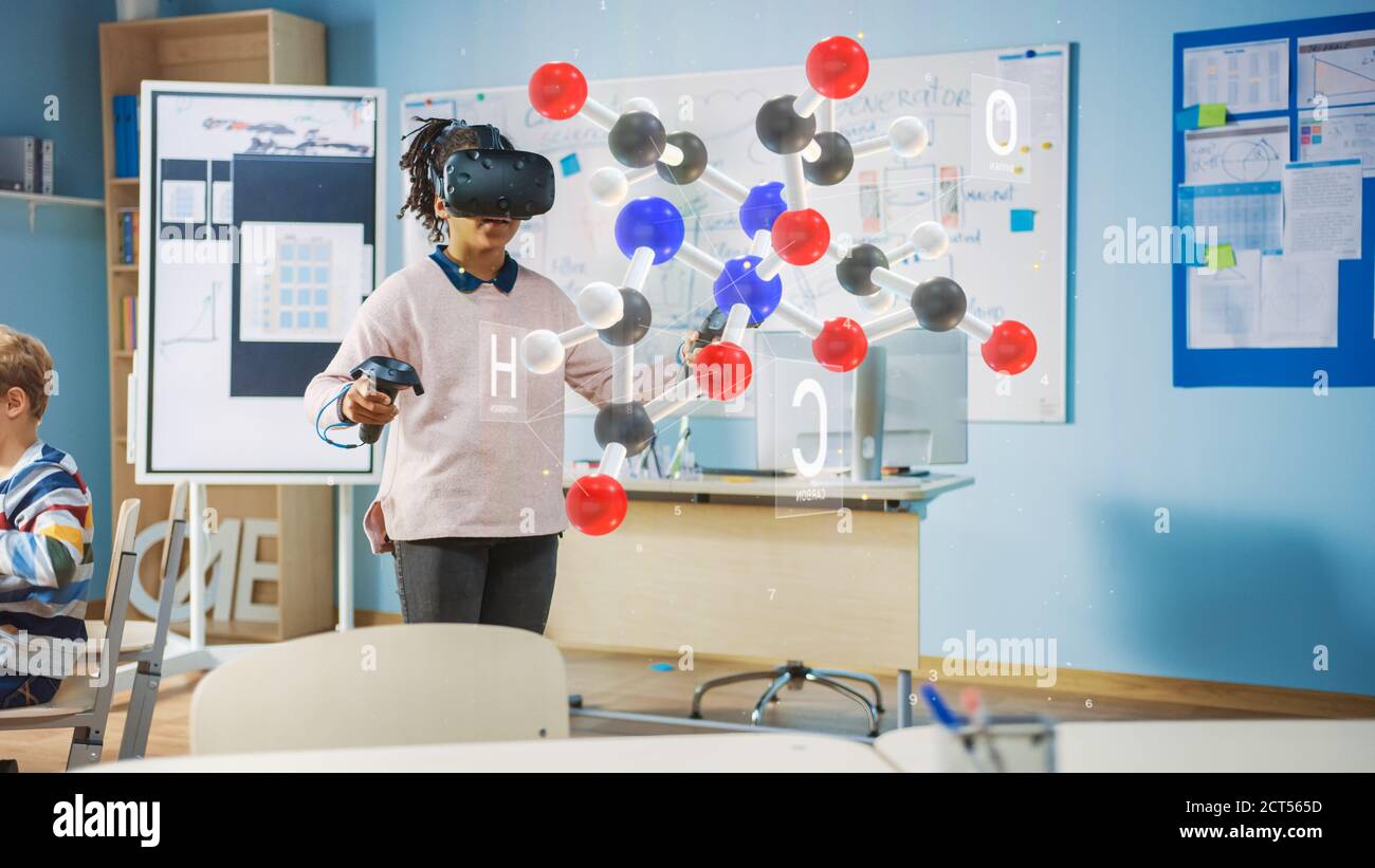 Cute Girl indossa le cuffie per realtà aumentata e utilizza i controller interagisce con 3D Molecule. Corso di scienze della scuola futuristica per i bambini che imparano dentro Foto Stock