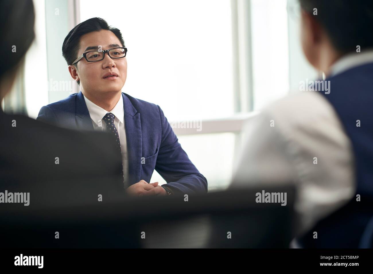 giovane uomo d'affari asiatico che parla con l'intervistatore durante l'intervista di lavoro Foto Stock