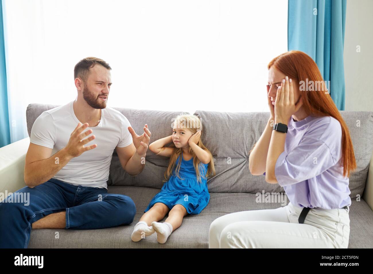 la bambina caucasica soffre di dispute tra i genitori in famiglia a casa, la donna rossa e il ragazzo sopportato discutono in presenza di figlia Foto Stock