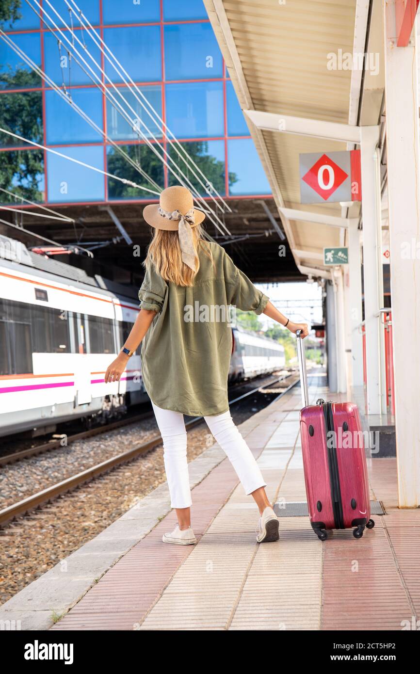 Vista posteriore di una donna anonima con valigia in piedi piattaforma e in  attesa di treno in giornata di sole sulla ferrovia stazione Foto stock -  Alamy
