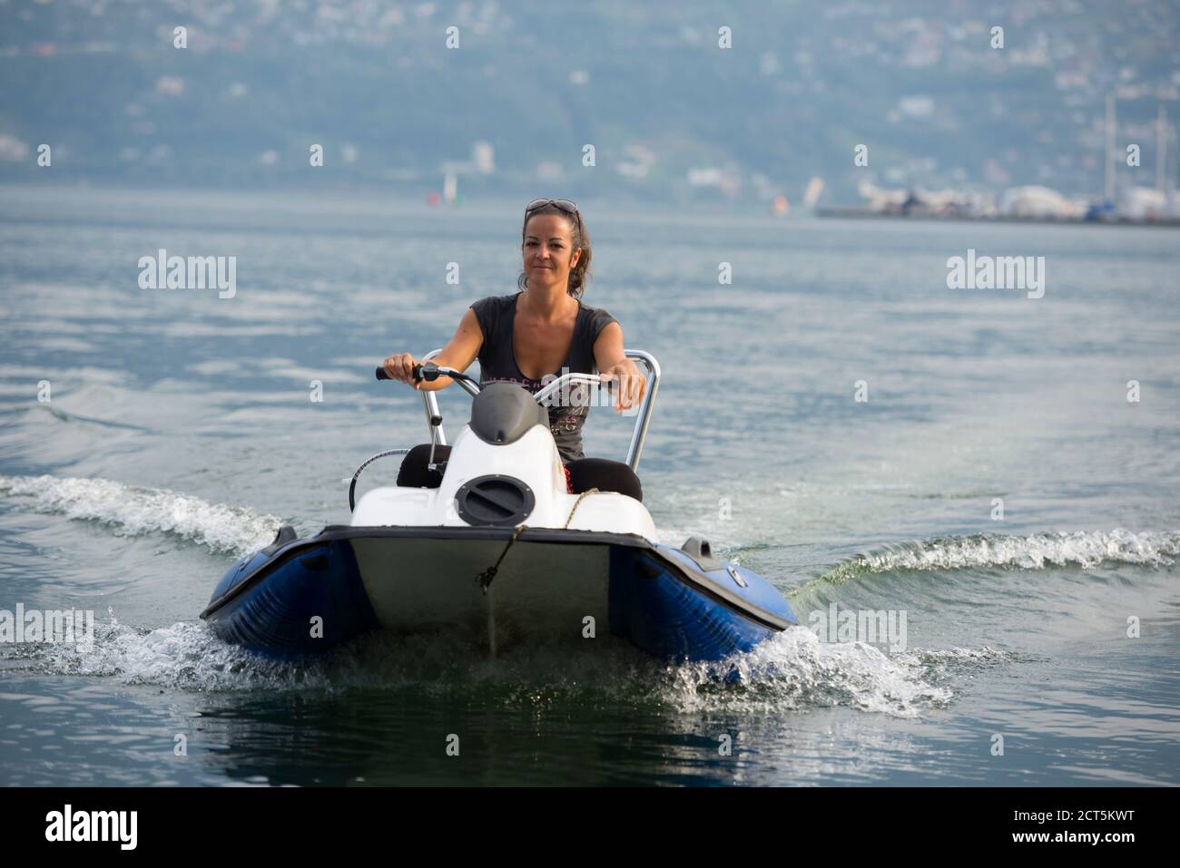Happy Woman alla guida di un moderno motoscafo sull'acqua in Ticino, Svizzera. Foto Stock