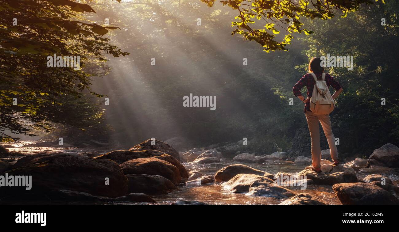Una donna esplora luoghi nuovi, magici e fantastici in tutto il mondo, circondati dalla natura e diffondendo le braccia per respirare e rilassarsi. Donna escursionista c Foto Stock