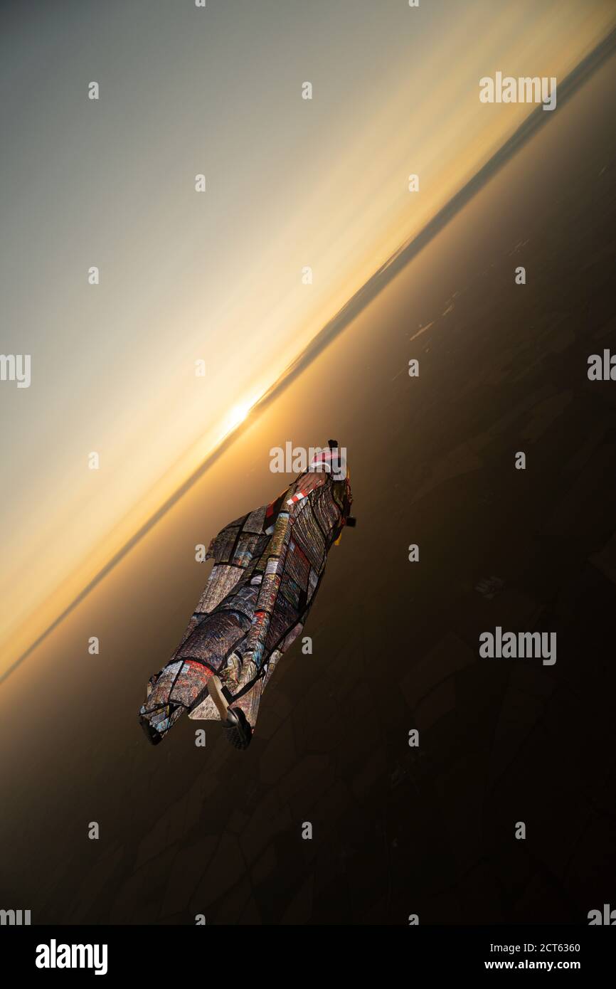 Tuta alata volante Skydiver in stile ritratto con flash sull'orizzonte del tramonto Foto Stock