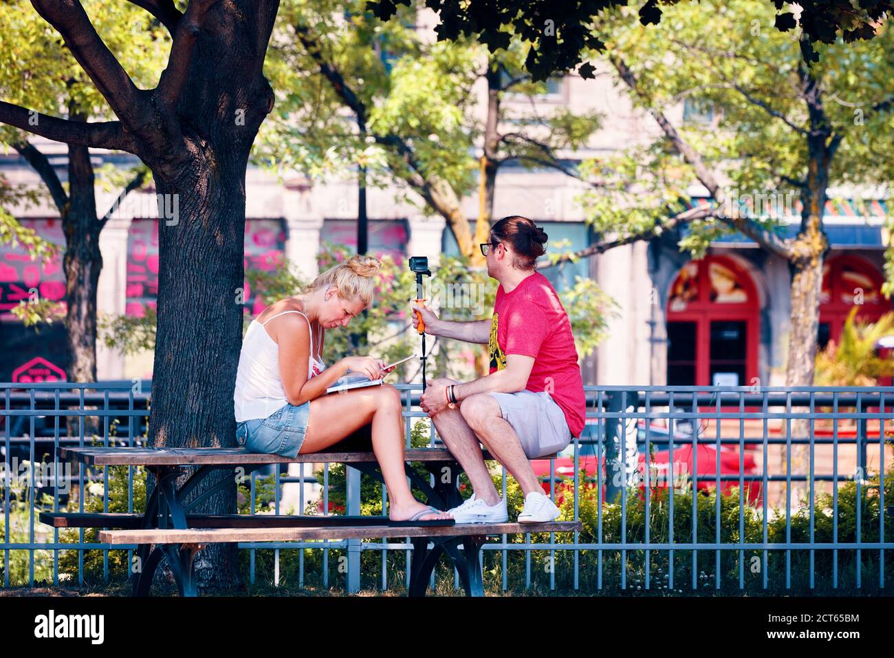 Montreal, Canada - Giugno, 2018: Giovane coppia seduta nel parco con smartphone e fotocamera gopro a Montreal, Quebec, Canada. Rapporto, tempo libero, t Foto Stock
